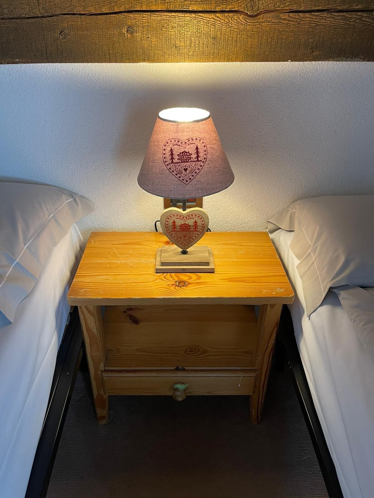 Una mesita de noche de madera con una lámpara y una decoración con forma de corazón.