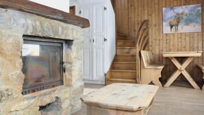 Una chimenea de piedra, una escalera de madera y un cuadro de un ciervo.