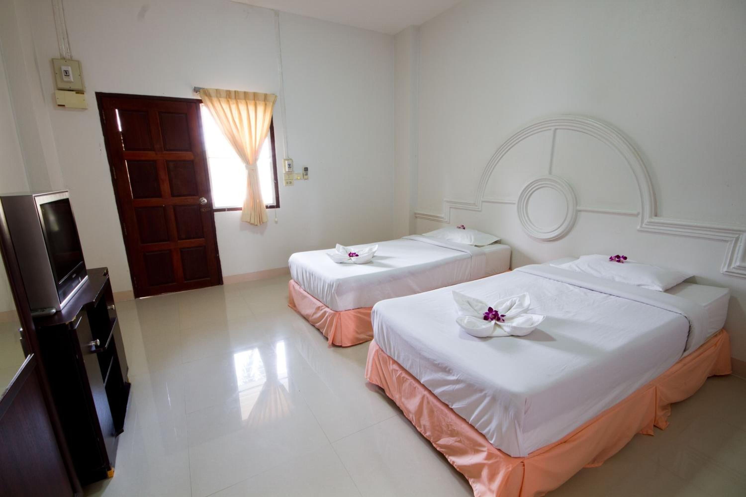 A hotel room with two beds, a TV, and a door leading to another room.