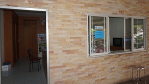 A room with a brick wall, a window with a sign, a chair, and a television. - A.P. Garden Hotel (Kalasin)