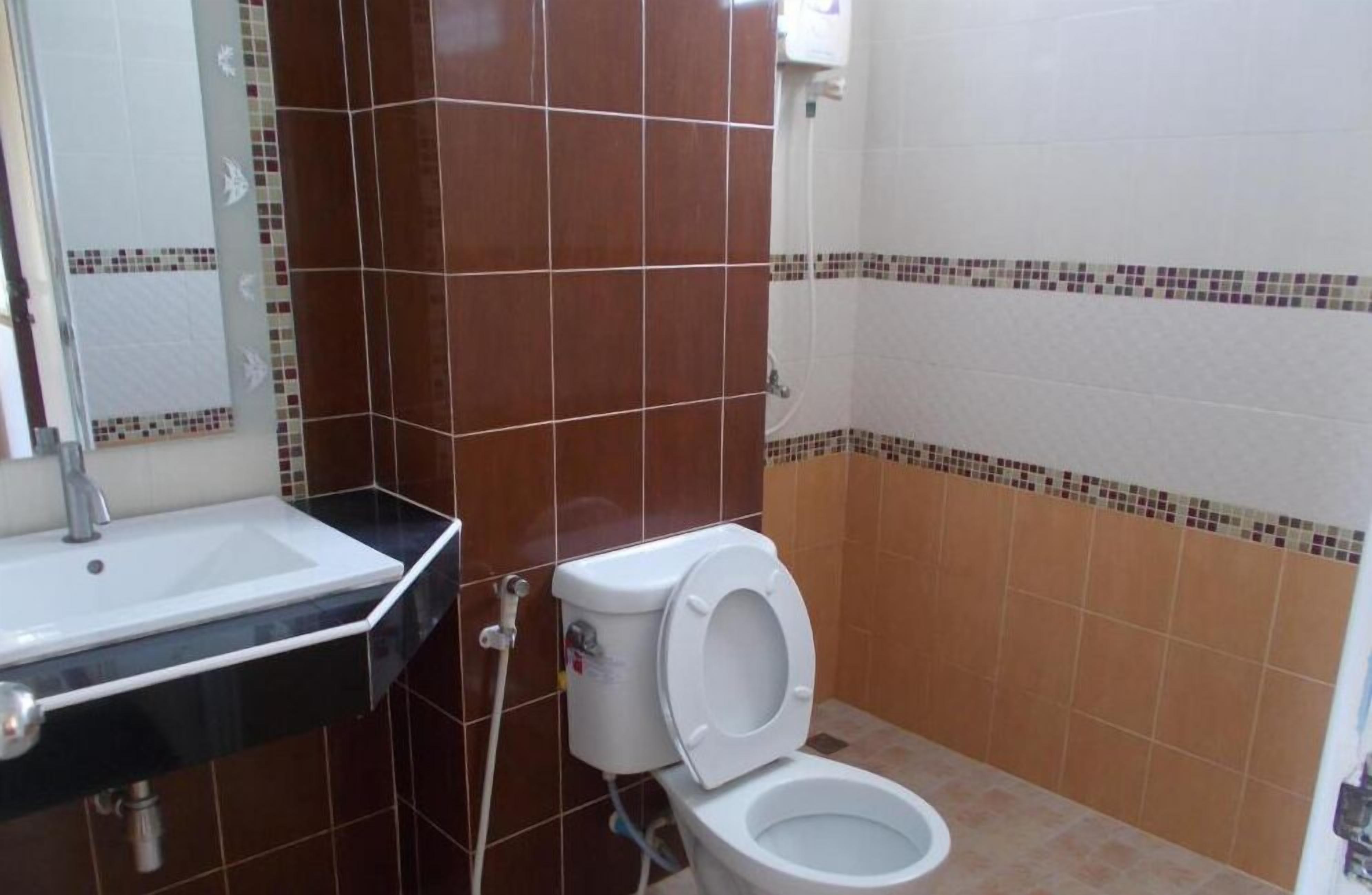 Un baño con un lavamanos blanco, inodoro y paredes con azulejos.