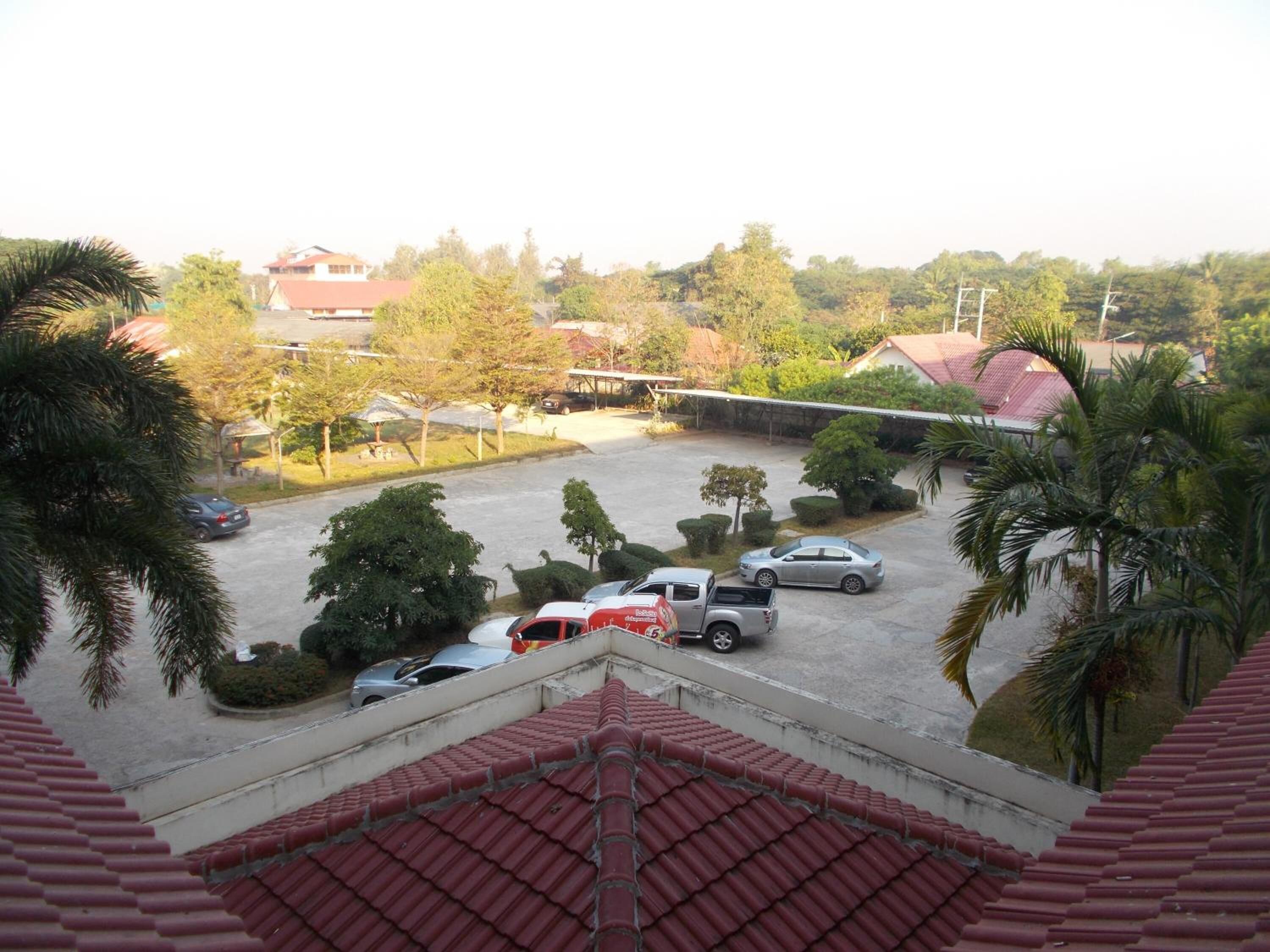 A parking lot with several cars and a truck, surrounded by trees and buildings.