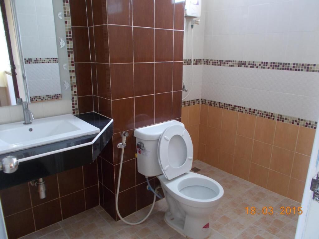A bathroom with a white sink, a toilet, and tiled walls.