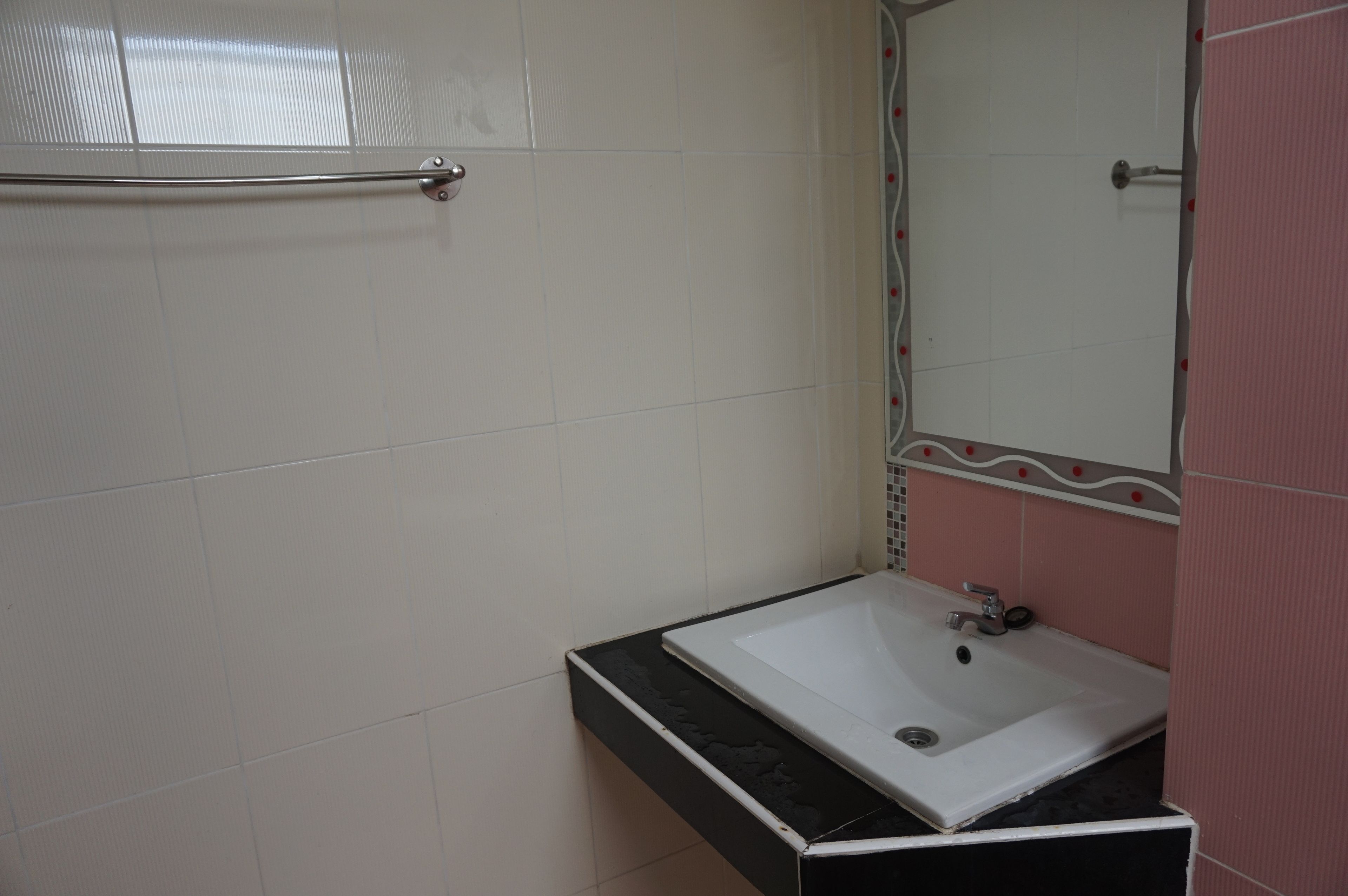 A bathroom with a white sink, a mirror, and a towel rack.