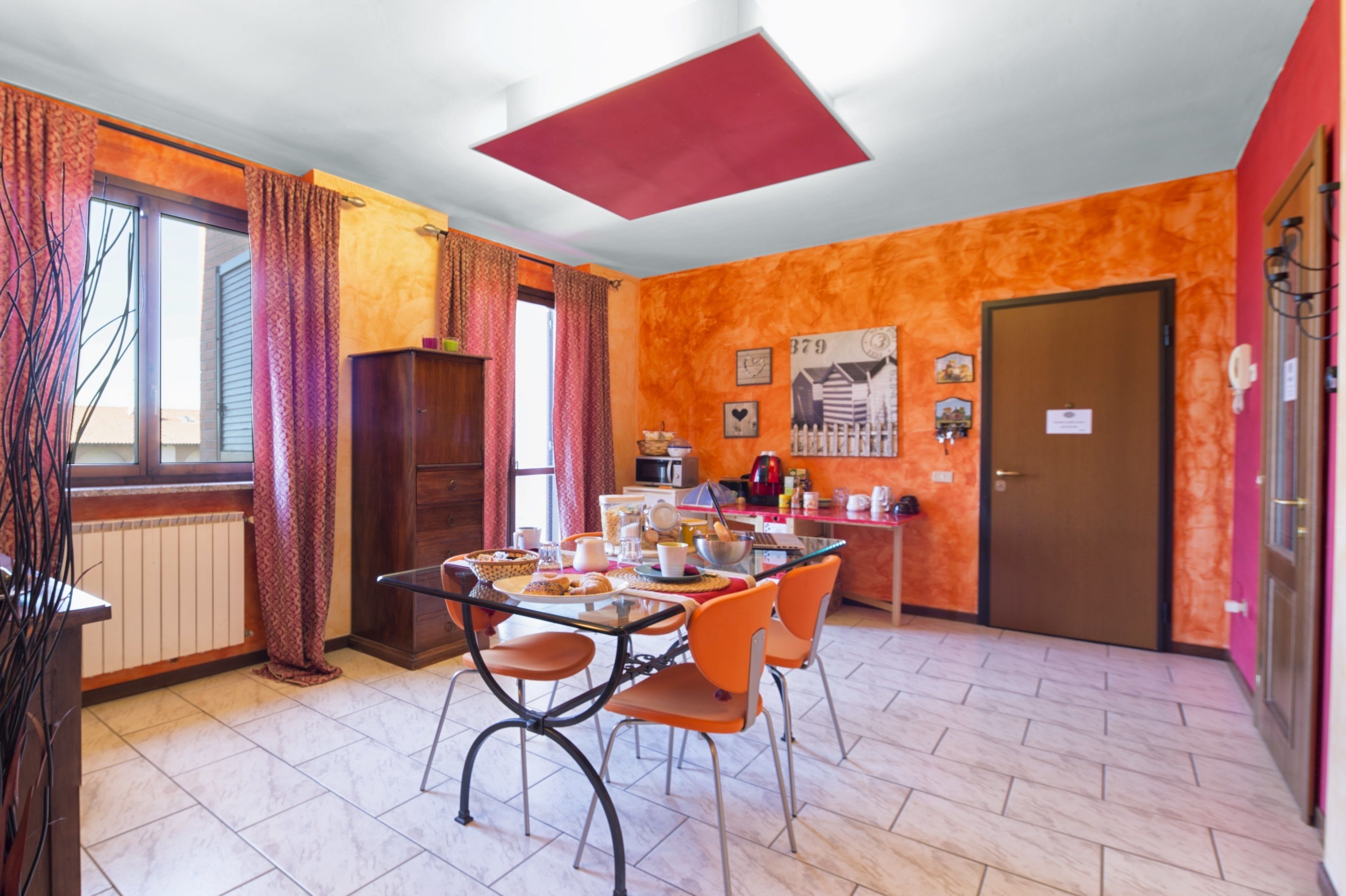 A dining area with a table set for four, a kitchen area with appliances, and a door leading to another room.