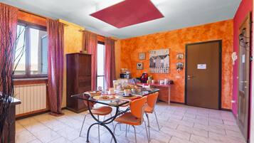 A dining area with a table set for four, a kitchen area with appliances, and a door leading to another room.