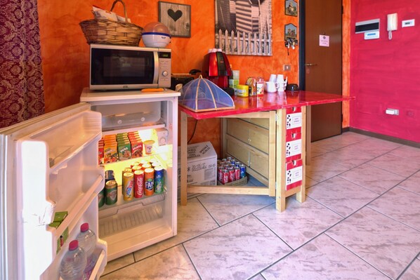 A compact kitchen with a microwave, refrigerator, and a small wooden table. - B&B La Casa di Miele (Marcignago)