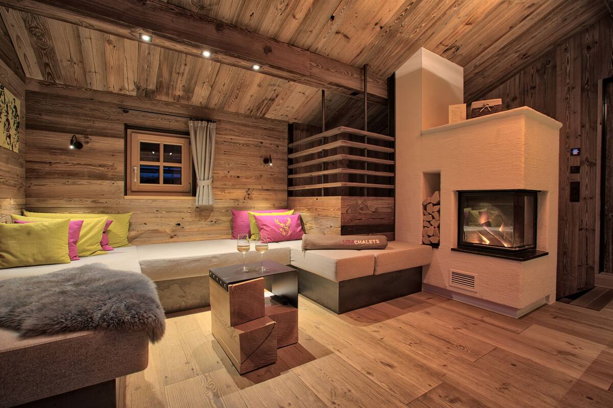 A cozy log cabin interior with a fireplace, wooden walls, a sofa, and a coffee table.