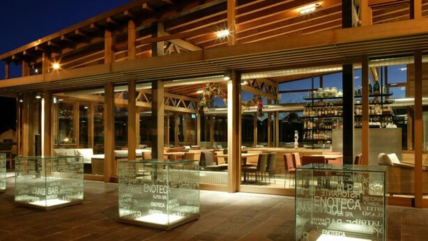 Un restaurant moderne avec une façade en verre, des poutres en bois et une terrasse.