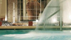 Une piscine agrémentée d’un élément décoratif aquatique et, au fond, une grande structure en forme de panier tressé.