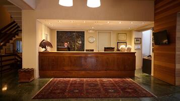 A reception area with a wooden counter, a large abstract painting, a clock, and a television on the wall.
