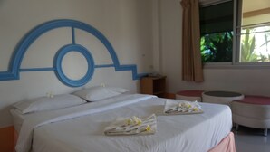 A hotel room with a large bed, a round headboard, a small table, and a window with curtains. - Ratchapreuk Resort (Kalasin)