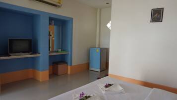 A hotel room with a bed, a television, a desk, and a blue refrigerator.