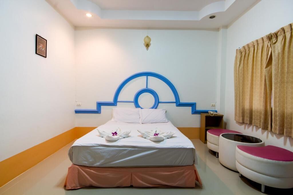A hotel room with a bed, a nightstand, a chair, and a window with curtains.