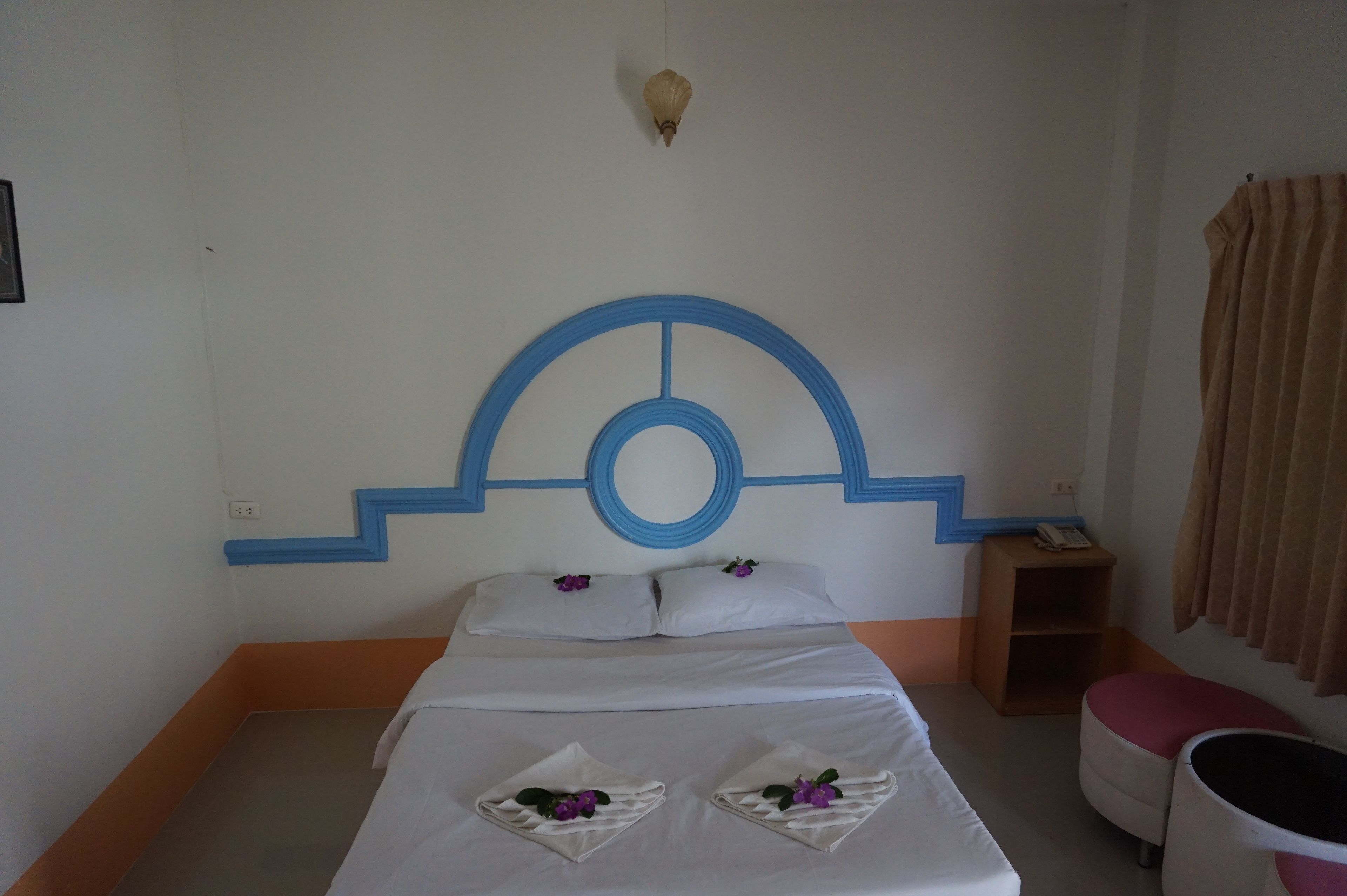 Quarto de hotel com cama, mesa de cabeceira, mesinha e uma cadeira.