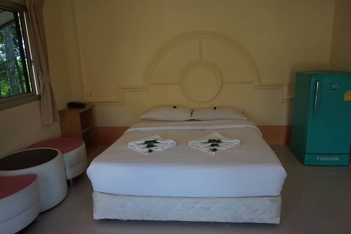 A hotel room with a bed, a refrigerator, and a window with curtains.