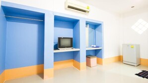 A room with blue walls, a white air conditioning unit, a television on a shelf, and a refrigerator. - Ratchapreuk Resort (Kalasin)