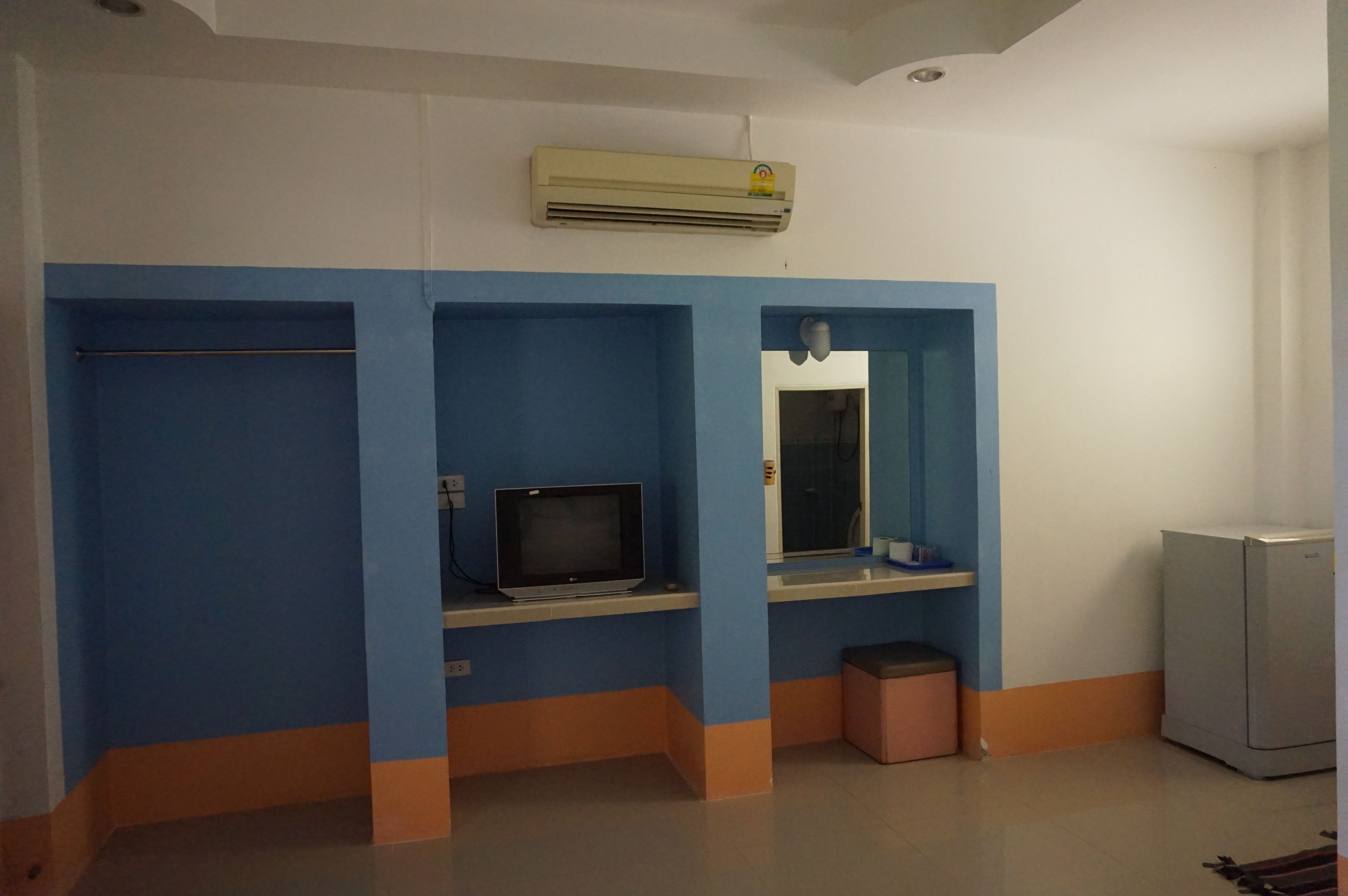 A bathroom with blue and white walls, a sink, a mirror, a television, and a trash bin.