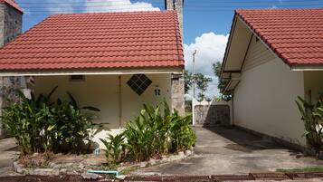 Two single-story buildings with red-tiled roofs, surrounded by lush greenery.