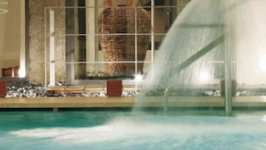 Une piscine agrémentée d’un élément décoratif aquatique et, au fond, une grande structure en forme de panier tressé.