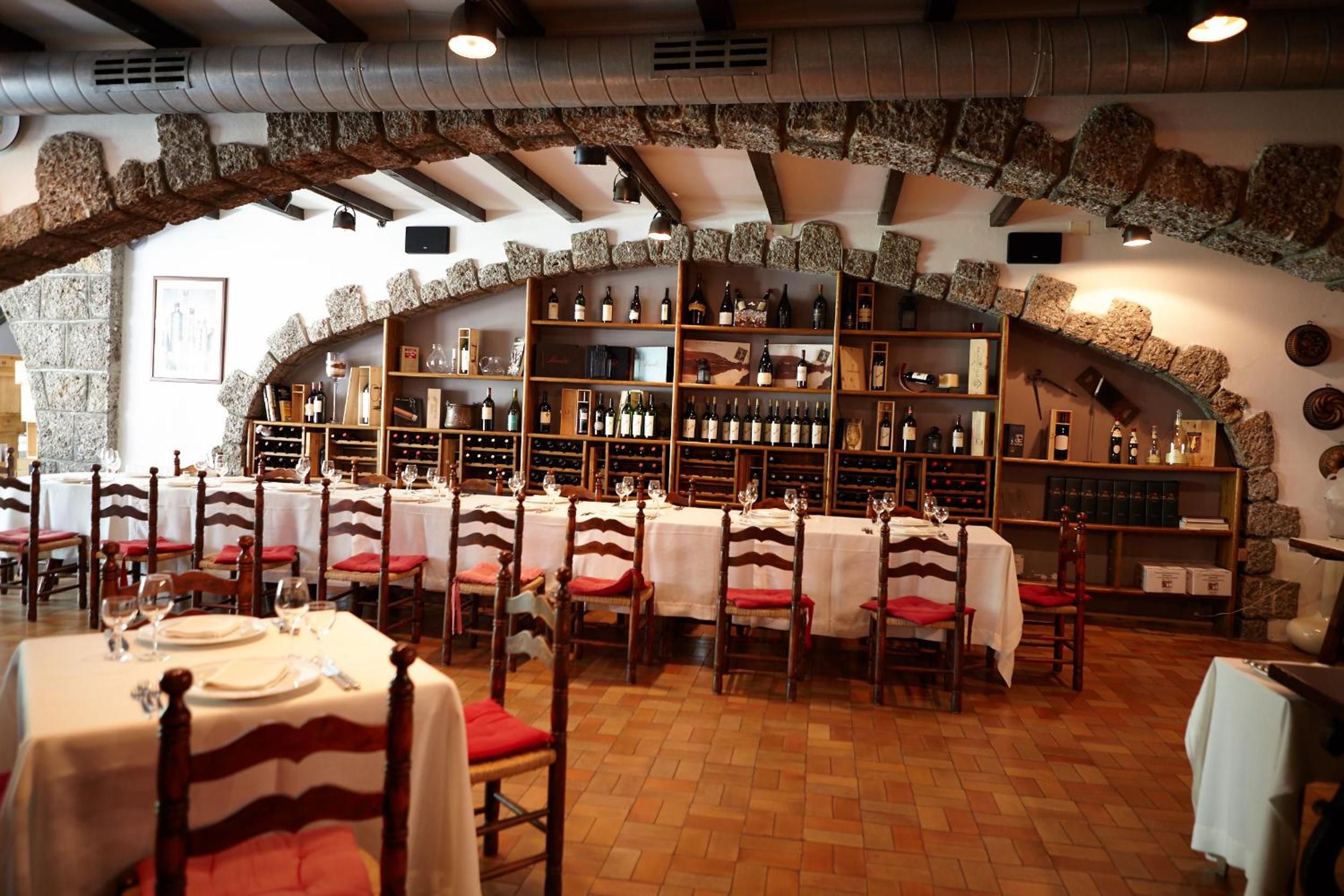 Un restaurant amb arcs de pedra, taules de fusta i prestatges per a vi.
