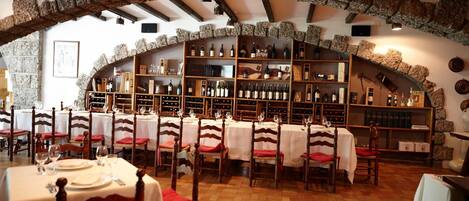 Un restaurante con arcos de piedra, mesas de madera y estanterías para vino.