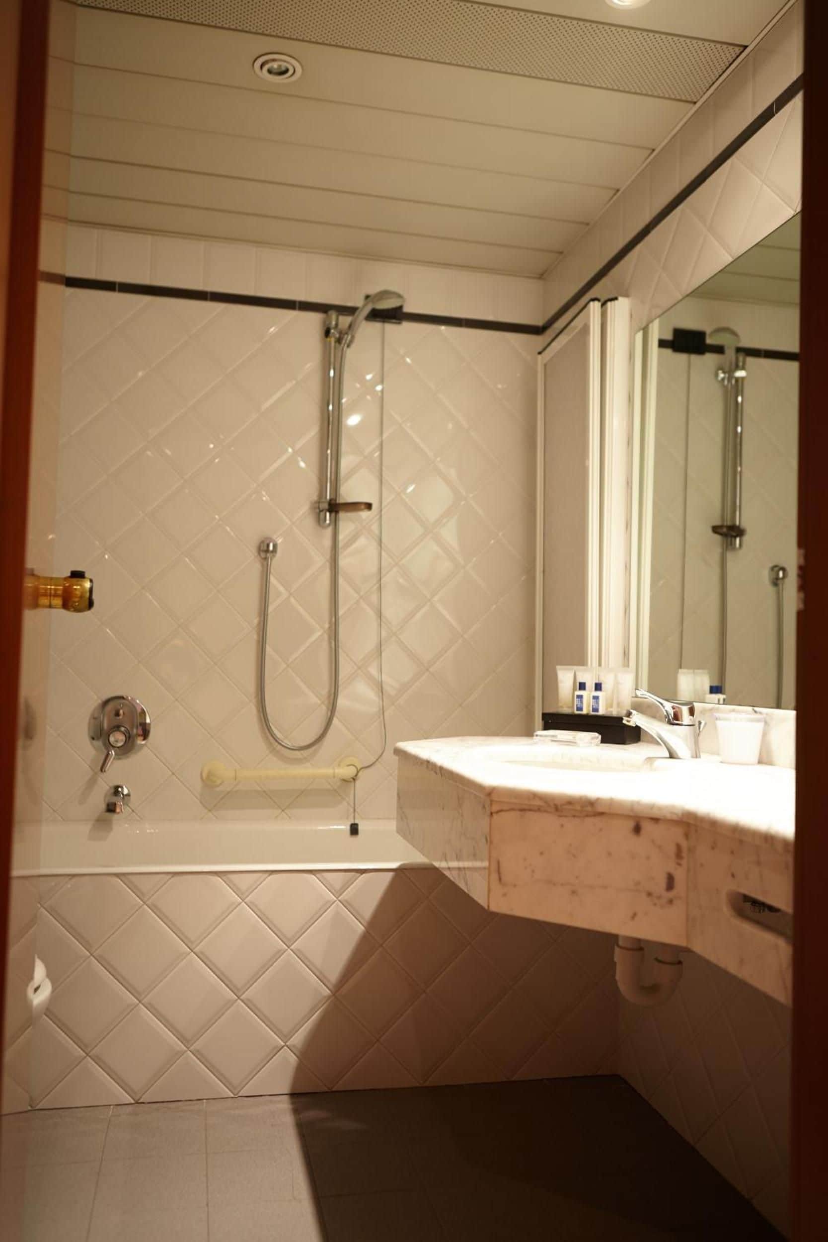 A bathroom with a shower, a bathtub, and a sink with a mirror.