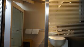 A modern bathroom with a large bathtub, a glass shower enclosure, and a small wooden stool.