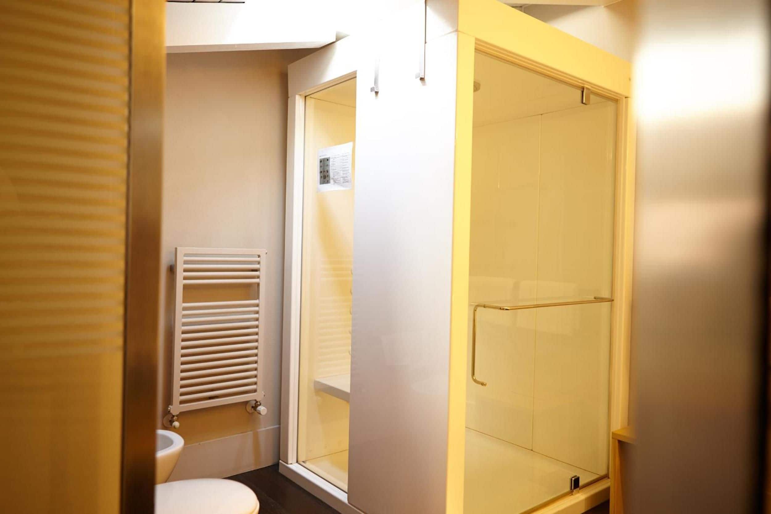 Un baño con inodoro, cabina de ducha de vidrio y barra para toallas.