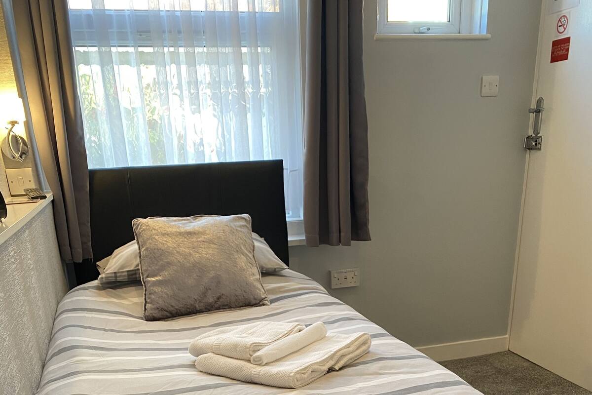A neatly made bed with striped bedding, a pillow, and folded towels.