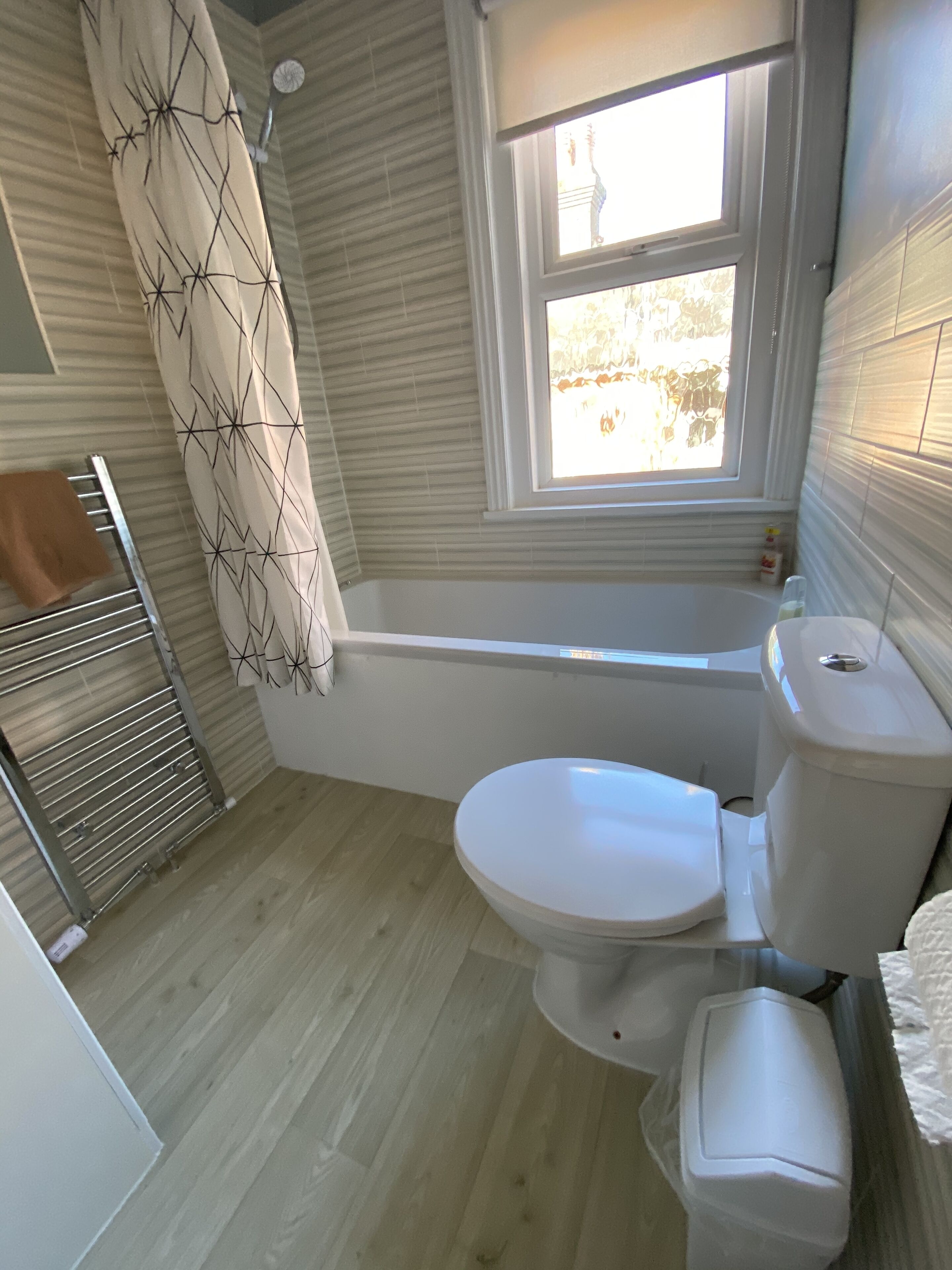 A bathroom with a bathtub, toilet, and a window.