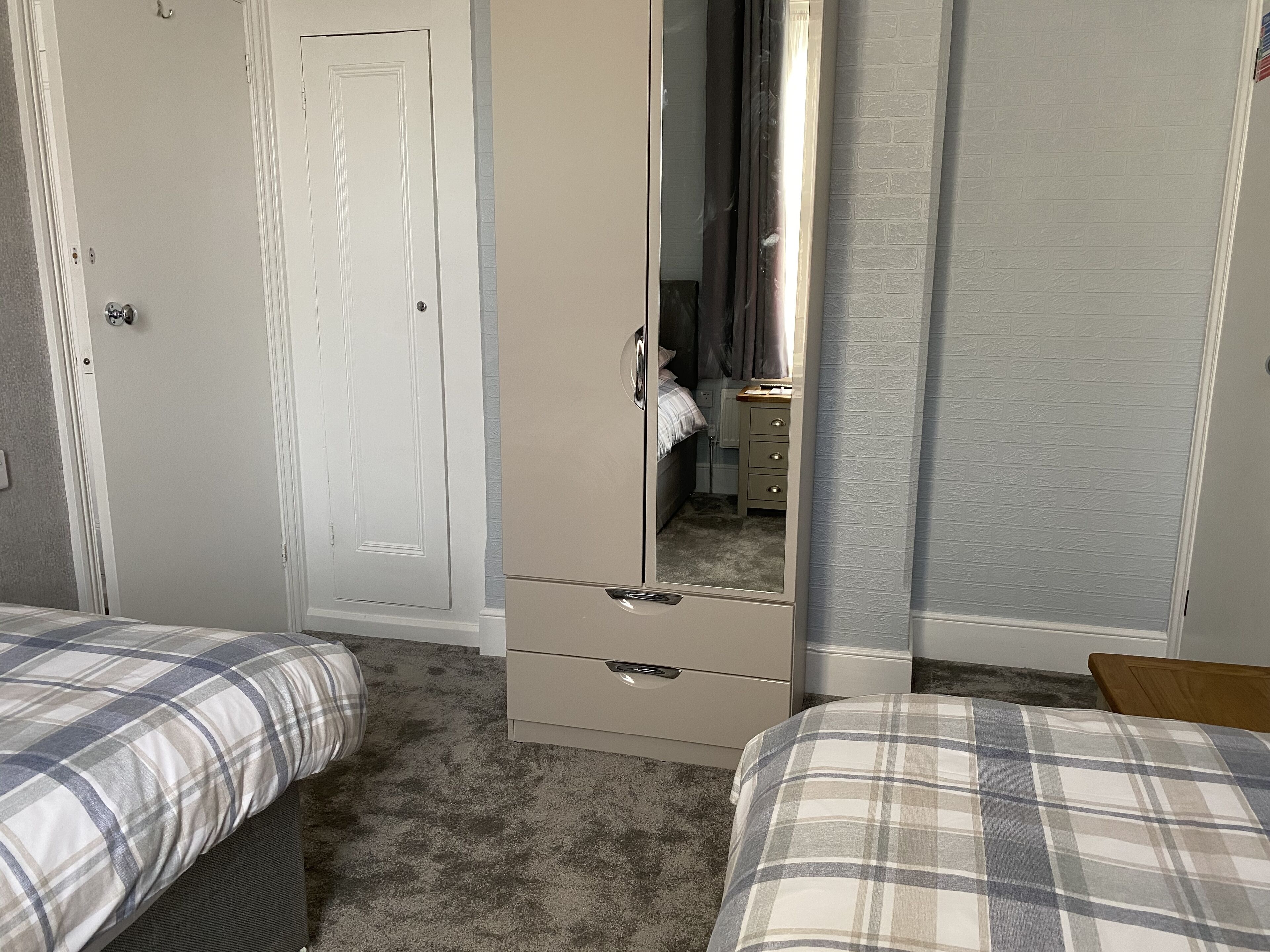 Een slaapkamer met twee bedden, een kledingkast en een spiegel.