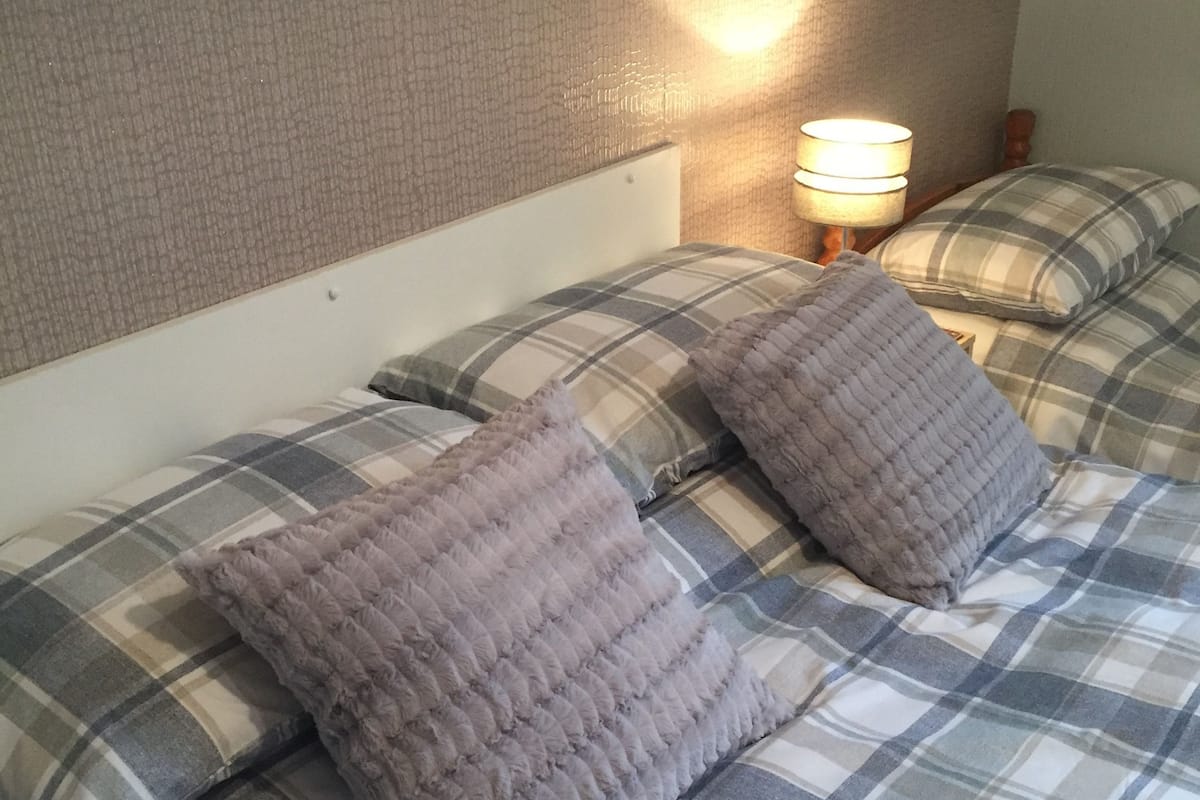 A bed with a plaid bedspread and two pillows.