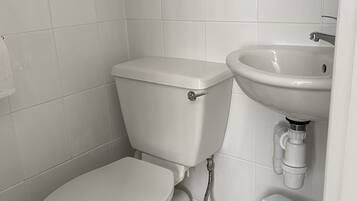 A modern bathroom with a toilet, sink, and storage unit.