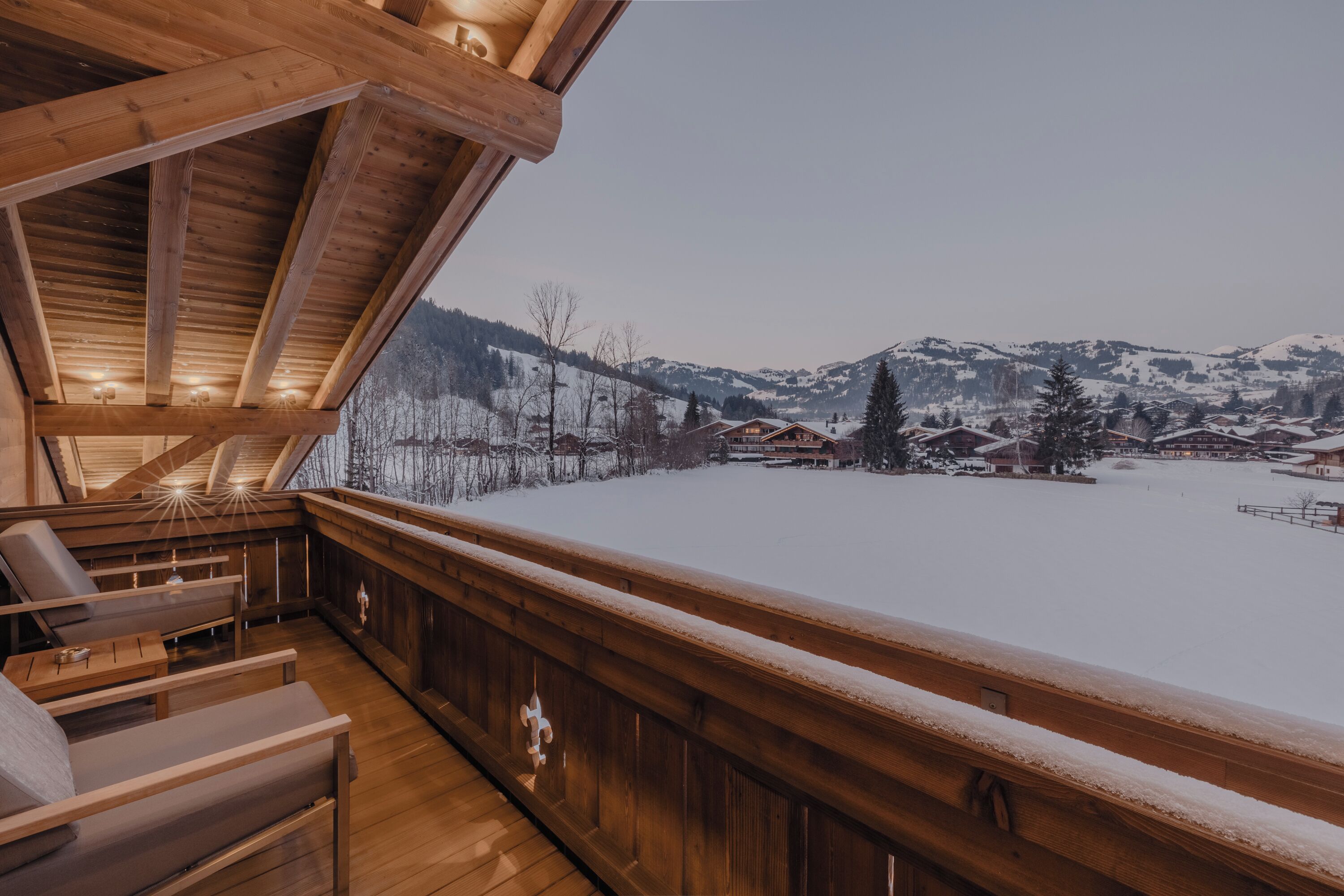 A wooden deck with a view of a snow-covered landscape and buildings.