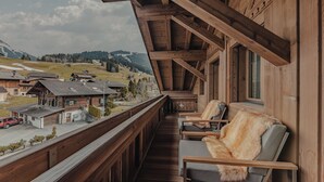 Een houten balkon met uitzicht op een bergachtig dorp.