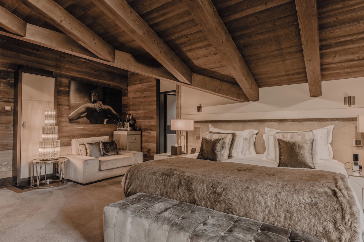 A spacious bedroom with a large bed, a sofa, and a wooden ceiling.