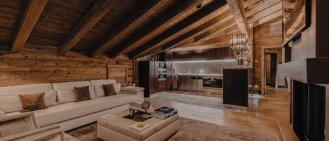 Amplia sala de estar con techo alto, vigas de madera, cocina moderna y un rincón de descanso acogedor.