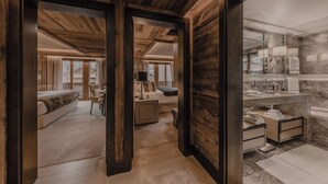 Een modern interieur met houten balkenplafond, een slaapkamer met een groot bed en een zithoek, en een badkamer met een marmeren aanrecht.