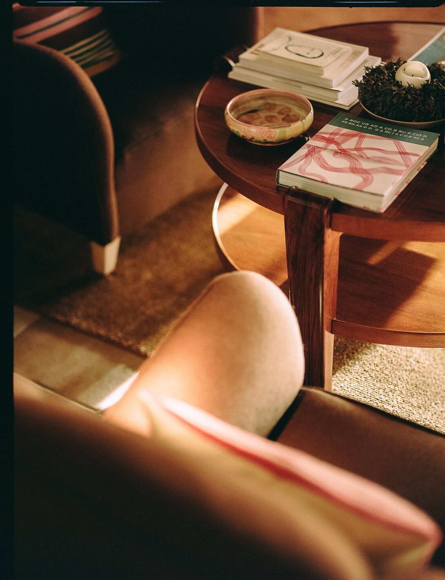 Une pièce chaleureuse avec une chaise en bois, une petite table ronde sur laquelle se trouvent un livre, un bol et une tasse.