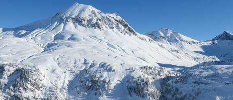 A snow-covered mountain with a ski lift and a cabin.