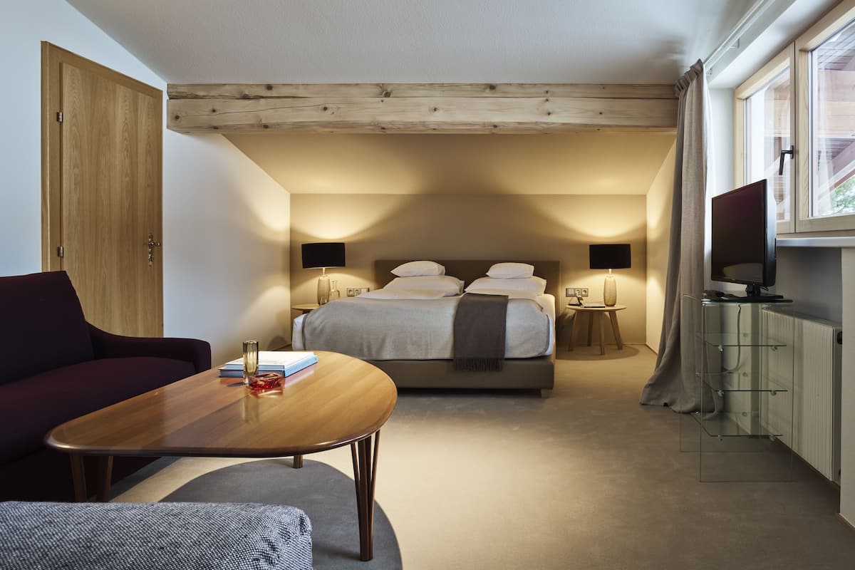 A hotel room with a bed, a TV, a desk, and a sofa.