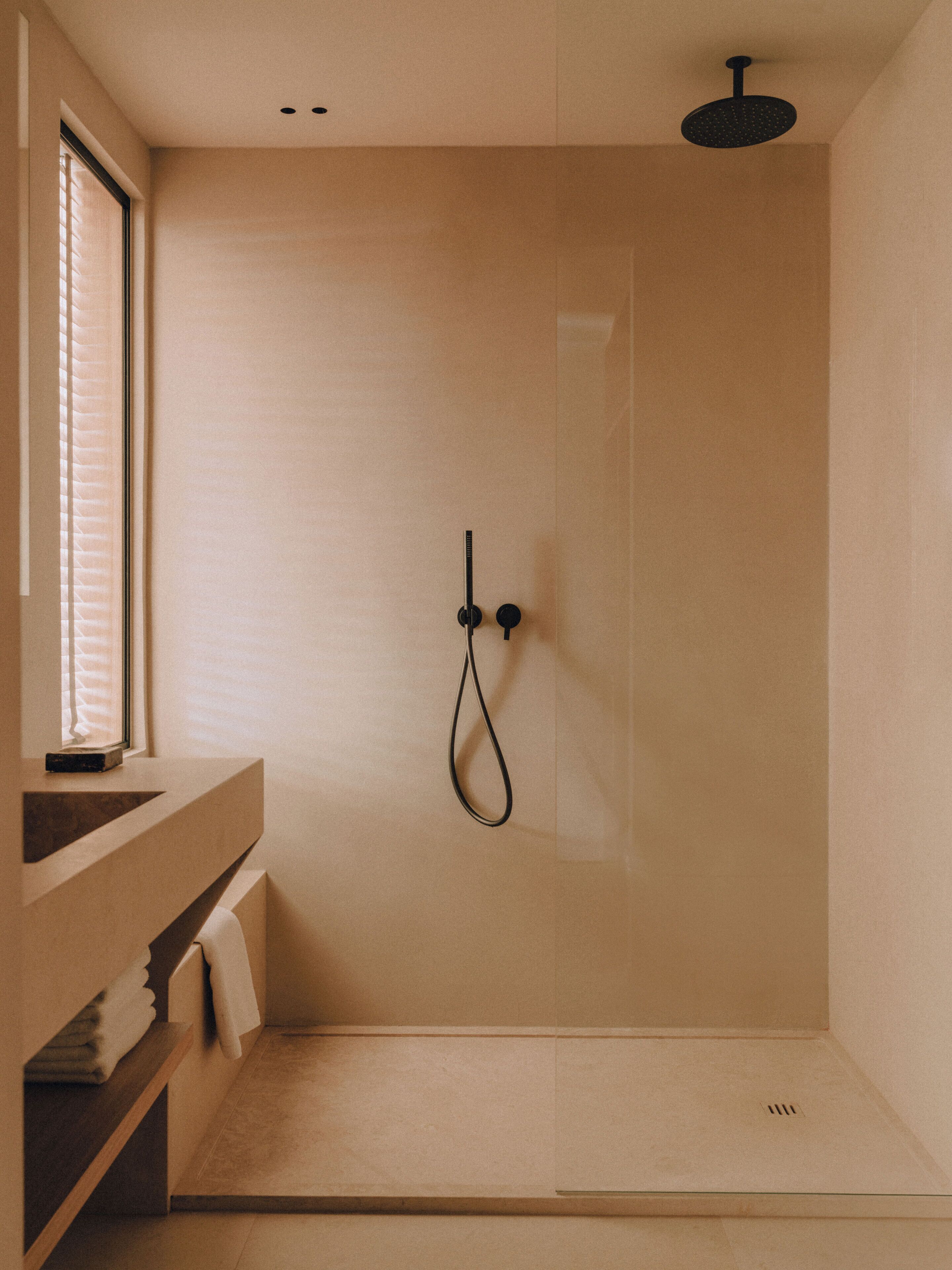 Une douche moderne dotée d’une porte en verre, d’un pommeau de douche à main et d’un porte-serviettes.