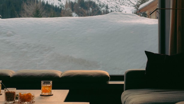 Um interior acolhedor com vista para uma paisagem montanhosa coberta de neve.