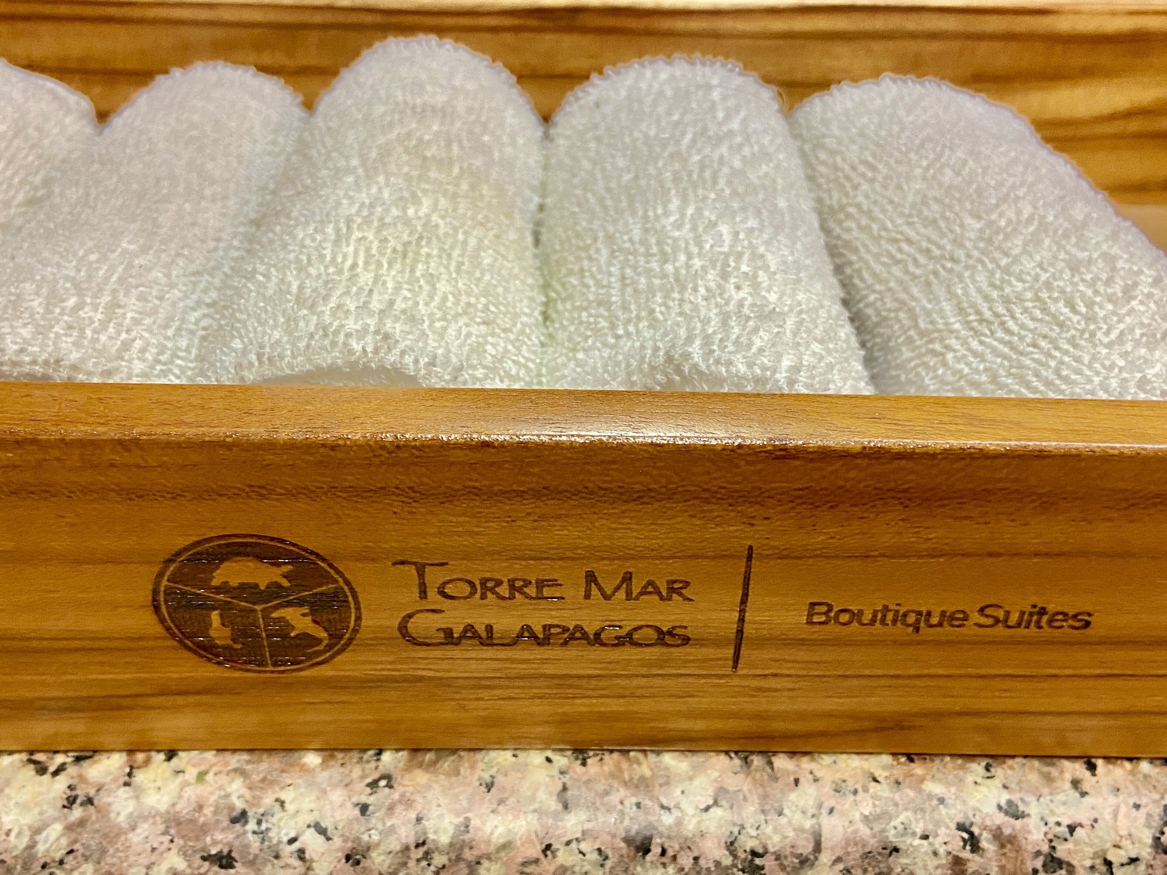 Una caja de madera con separadores de espuma y el texto "Torre Mar Galapagos Boutique Suites".