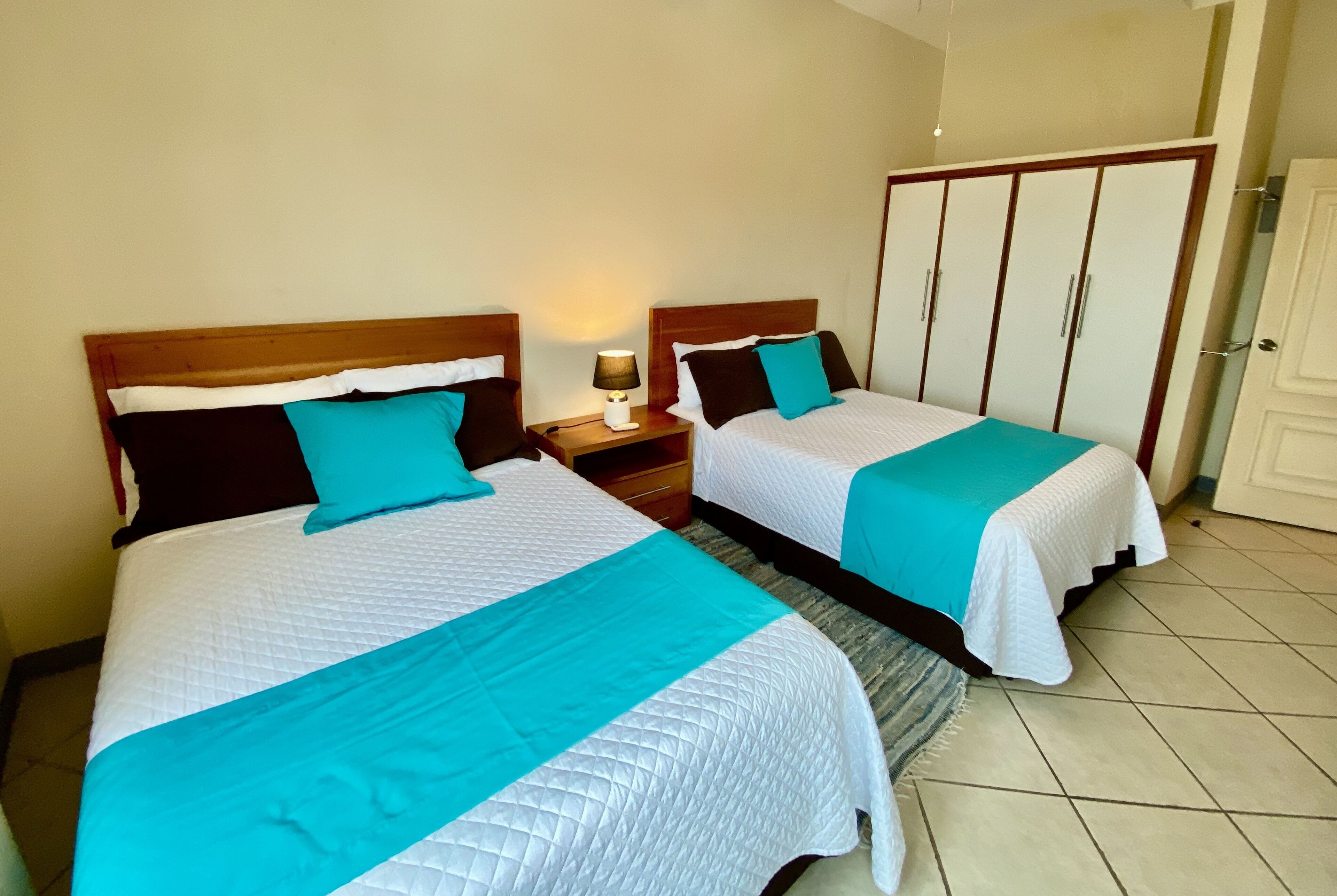 Two twin beds with matching headboards and nightstands, a wardrobe, and a door.