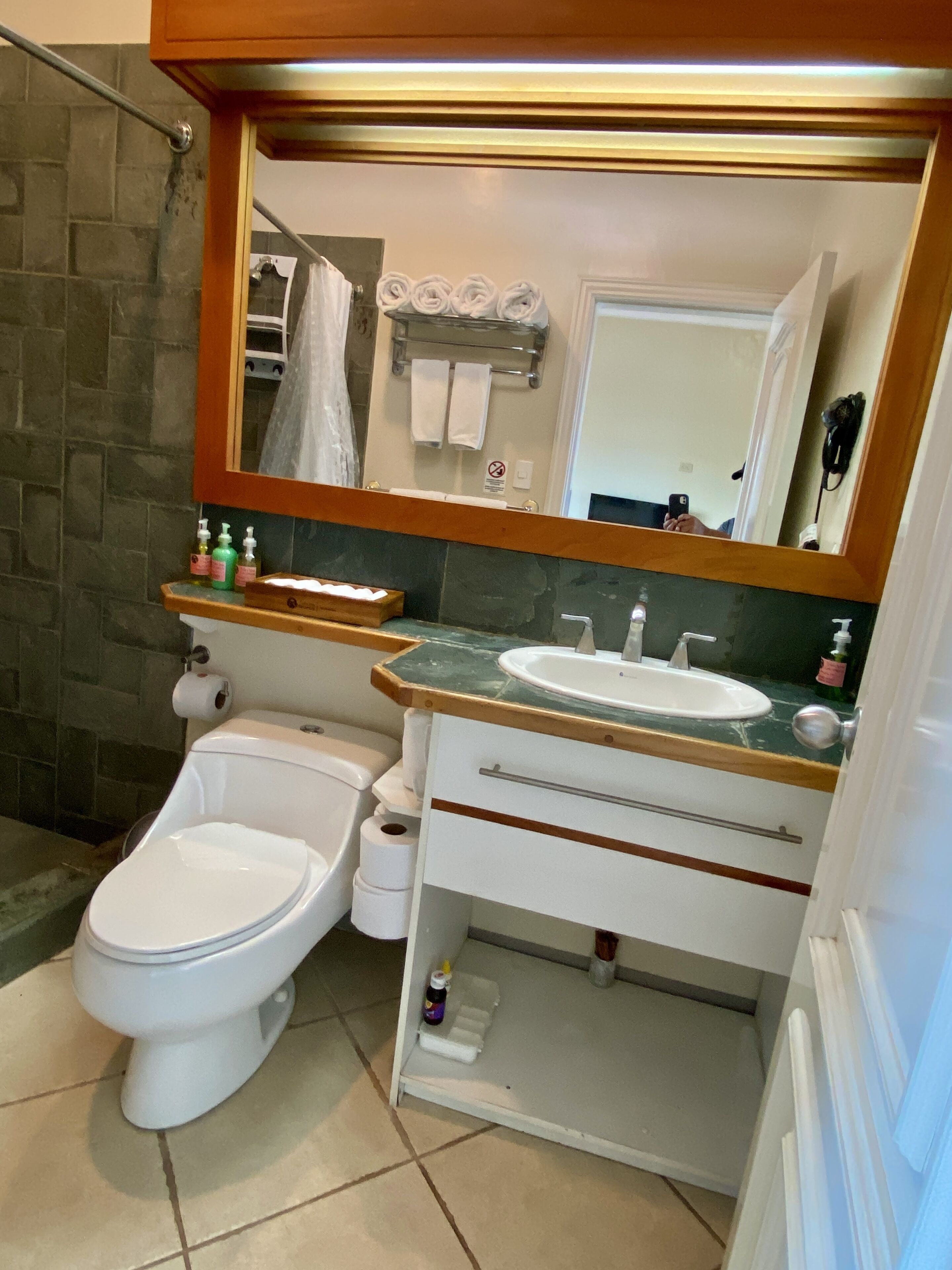 A bathroom with a toilet, bidet, sink, mirror, and towel rack.