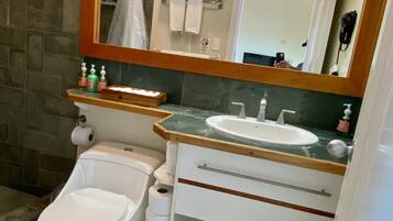 A bathroom with a toilet, bidet, sink, mirror, and towel rack.