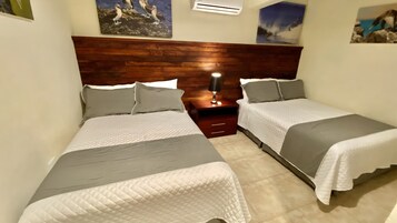A bedroom with two beds, wooden headboard, bedside tables, and wall art.