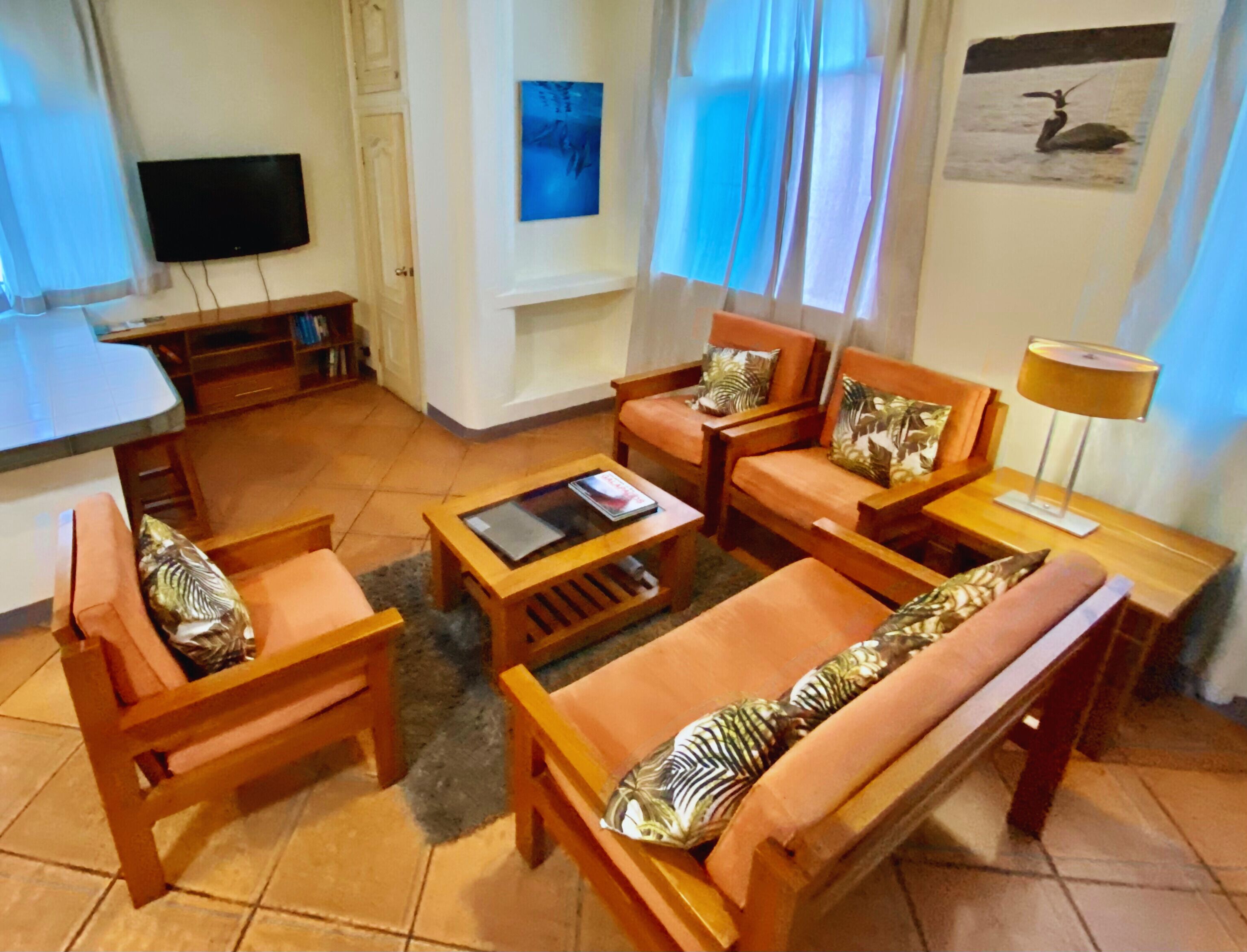 Una sala de estar con muebles de madera, un televisor de pantalla plana, un cuadro y una lámpara.